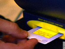 A voter slides her voter registration card into an e-voting machine.