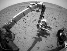 The Spirit rover reaches for Martian soil for the first time.